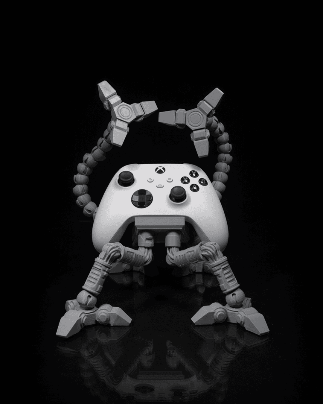Gray articulated controller holder with Xbox controller, robotic arms raised.