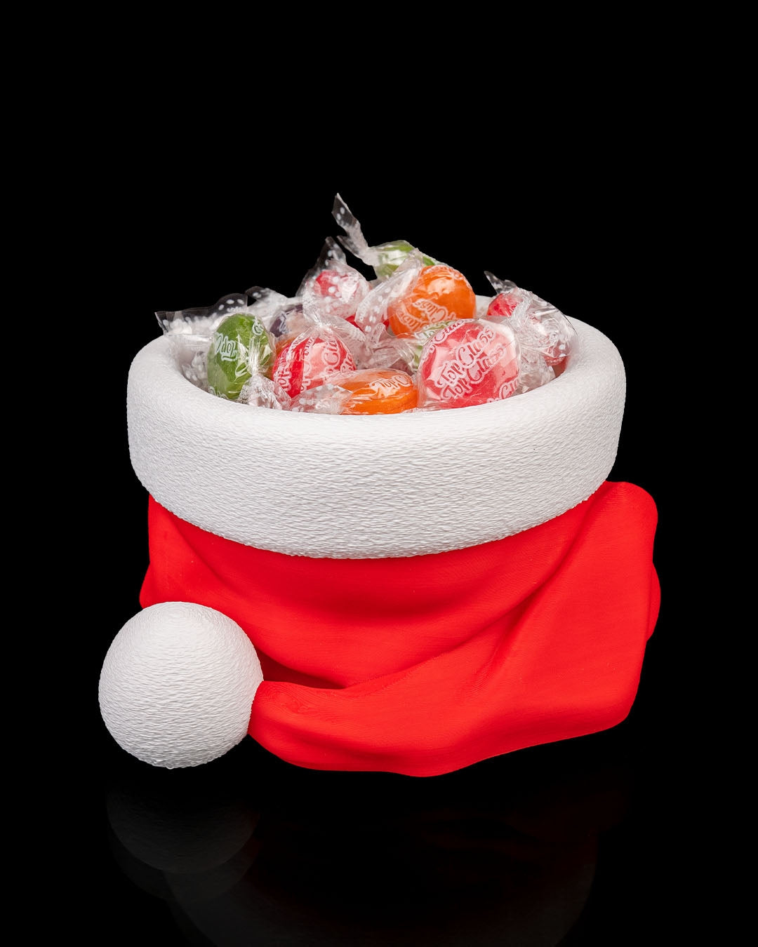 3D printed Santa’s Snack Hat Bowl filled with candy on a black background