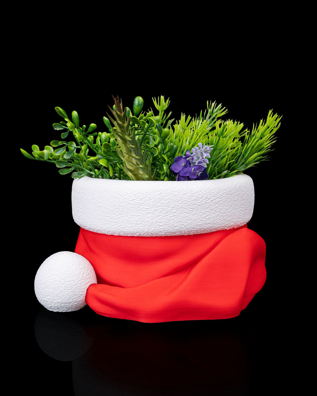3D printed Santa’s Snack Hat Bowl filled with a plant on a black background.