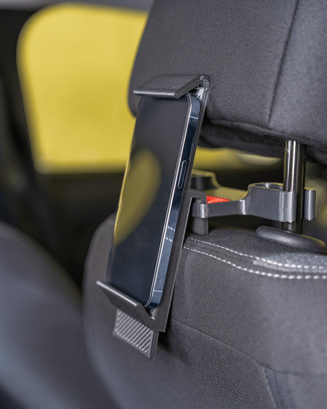 Phone holder component of AutoEase Complete Passenger Kit mounted behind headrest with phone