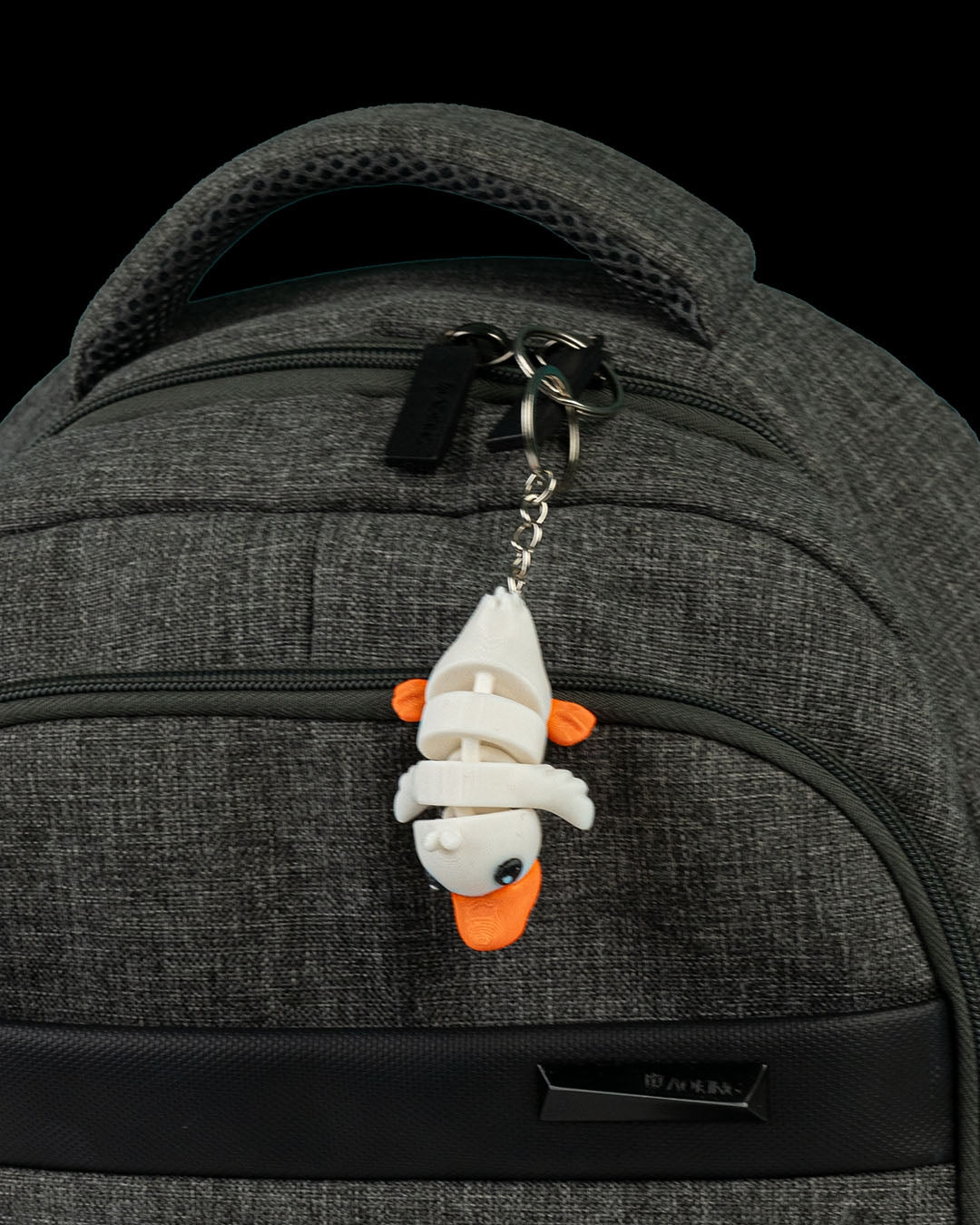 Cute Flexi Duck keychain attached to a backpack zipper, showing its flexible articulated body.