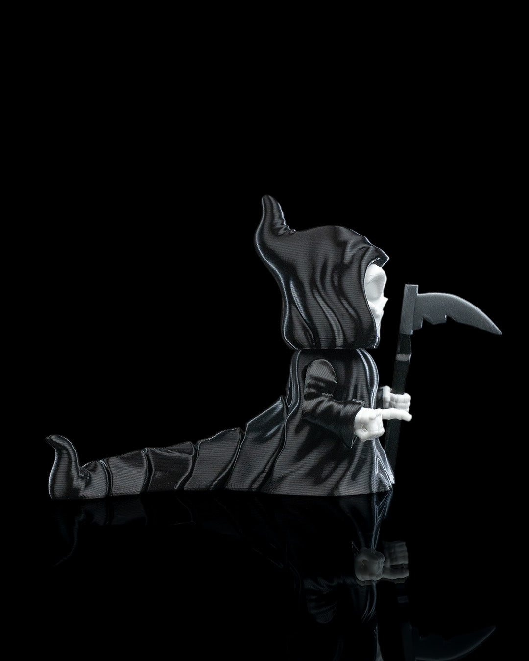 side view of 3D printed Grim Reaper flexi figurine named Death Wiggles, with skull face, hooded cloak, removable scythe, and flowing flexi cape.