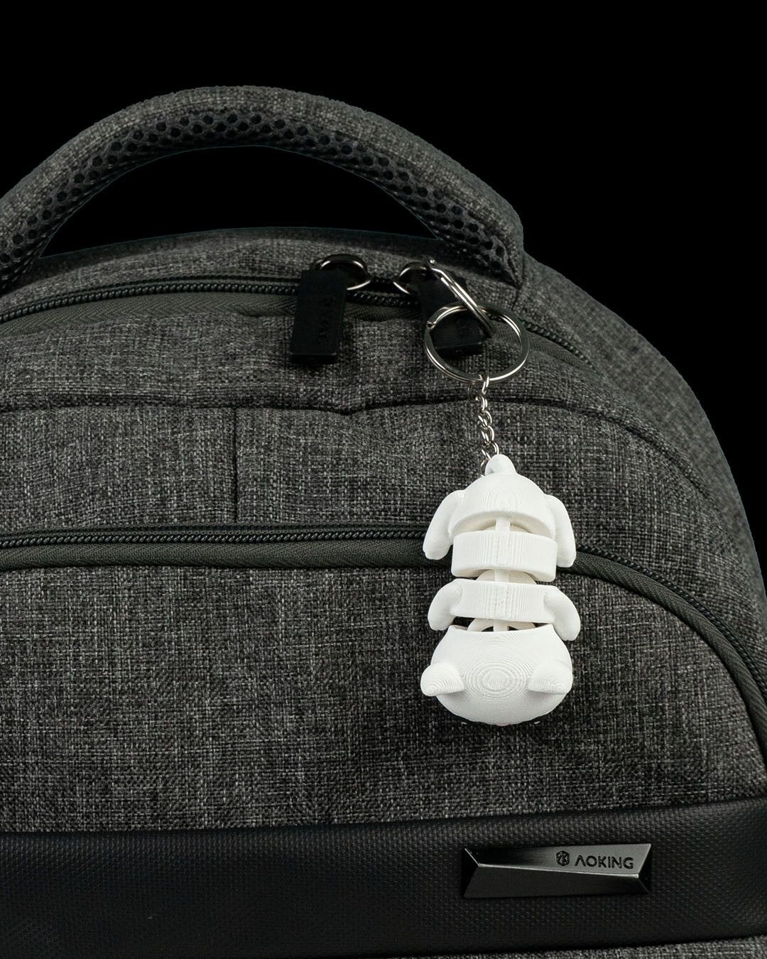 Flexi Cat keychain attached to a gray backpack, showing the articulated 3D printed cat hanging from a metal keyring.