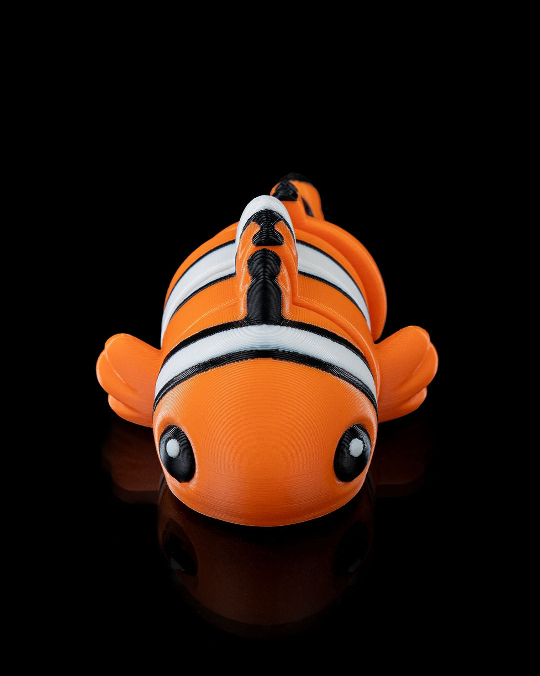 Front view of a 3D printed flexi clownfish with bright orange, white, and black stripes.