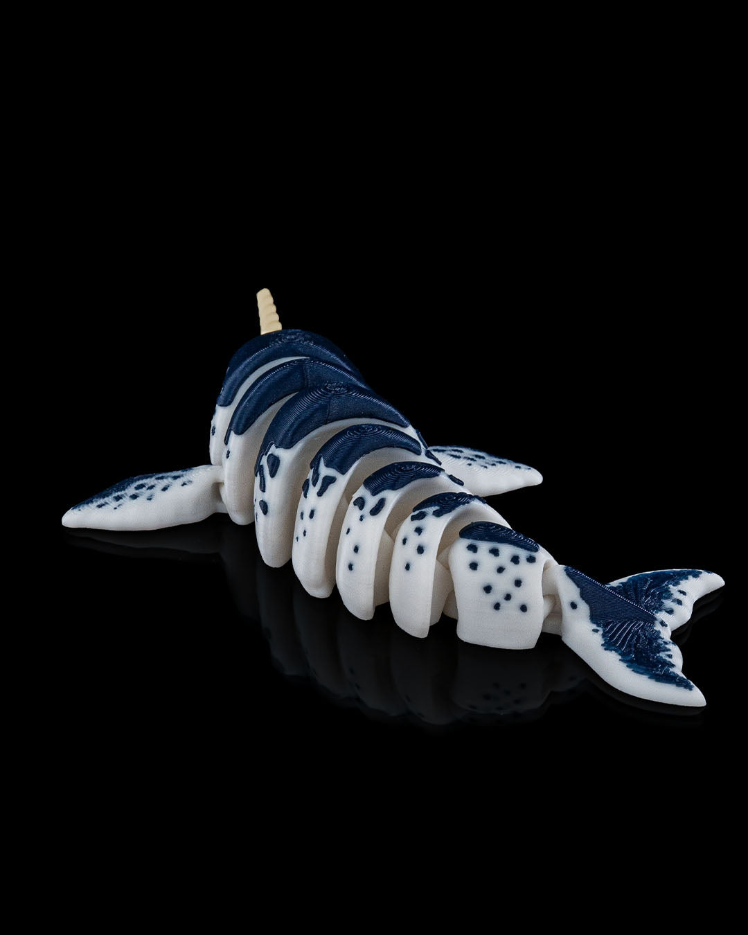 3D printed Flexi Narwhal toy shown in a rear-angled view with blue-and-white coloring and articulated body.