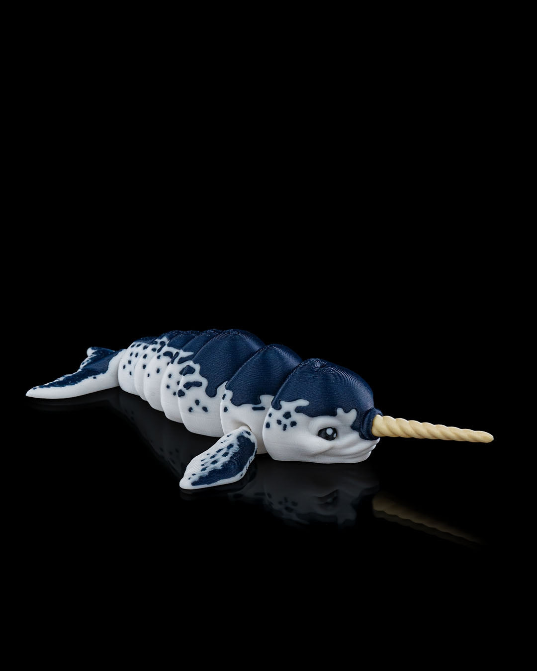 Side angled view of the articulated Flexi Narwhal toy displaying its segmented body and detailed fins.