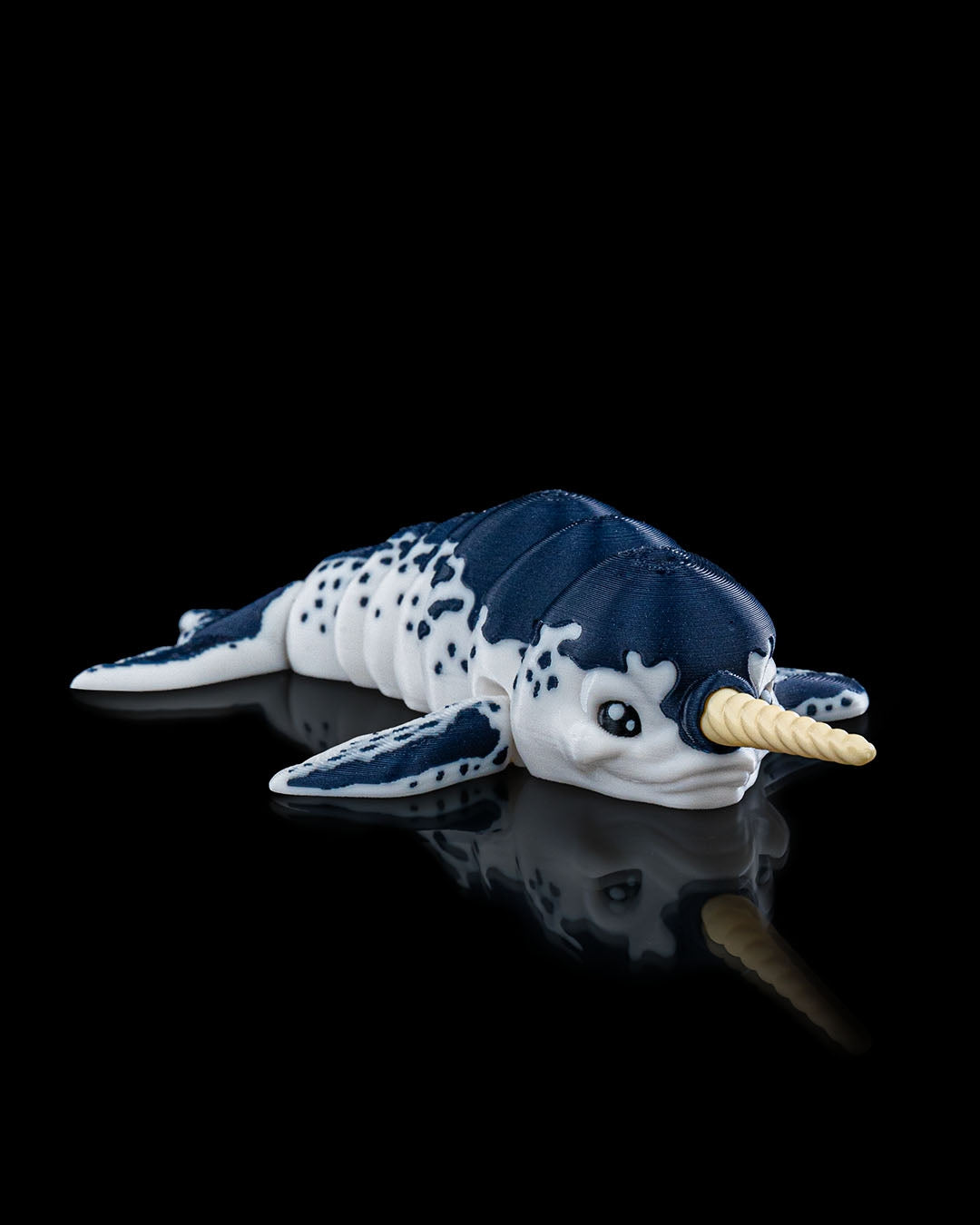 Angled front view of the articulated Flexi Narwhal toy displaying its segmented body and detailed fins.