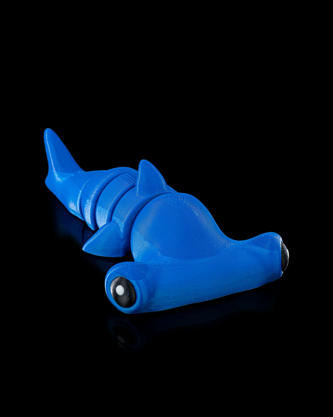 3D printed blue flexi hammerhead shark toy shown on black background with articulated segments.
