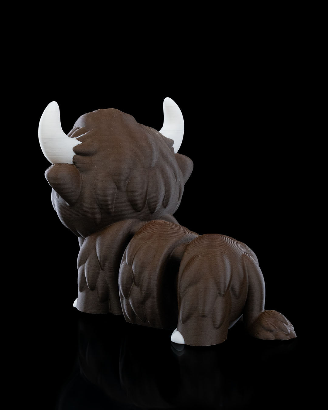 3D printed articulated Highland Cow figure, rear view, approximately 10cm tall, with detailed fur texture and white horns.