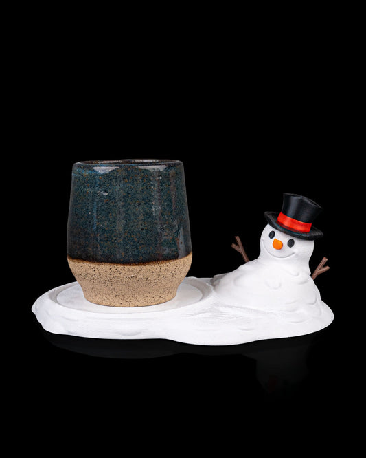 Meltproof Snowman Coaster holding a ceramic mug, showing size and functionality.