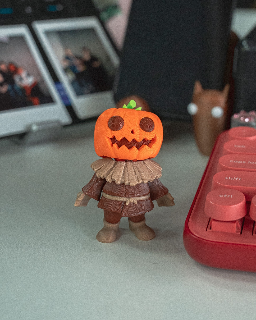 Front view of the 3D-printed Scarecutie Scarecrow figurine with pumpkin head and textured clothing on a desk.