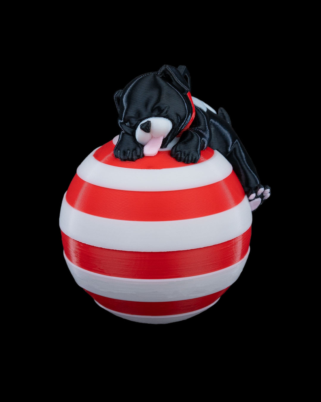 3D printed sleeping dog ornament resting on a red and white striped candy cane ball.